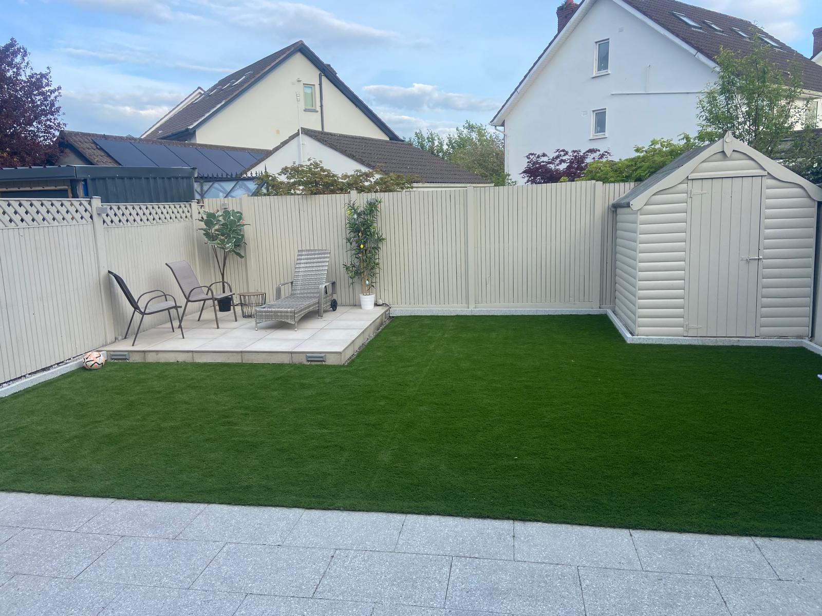 Completed artificial grass garden installation with patio and garden shed